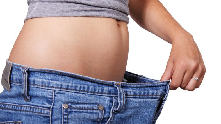 Photo of someone's waistline showing jeans much too large after weight loss